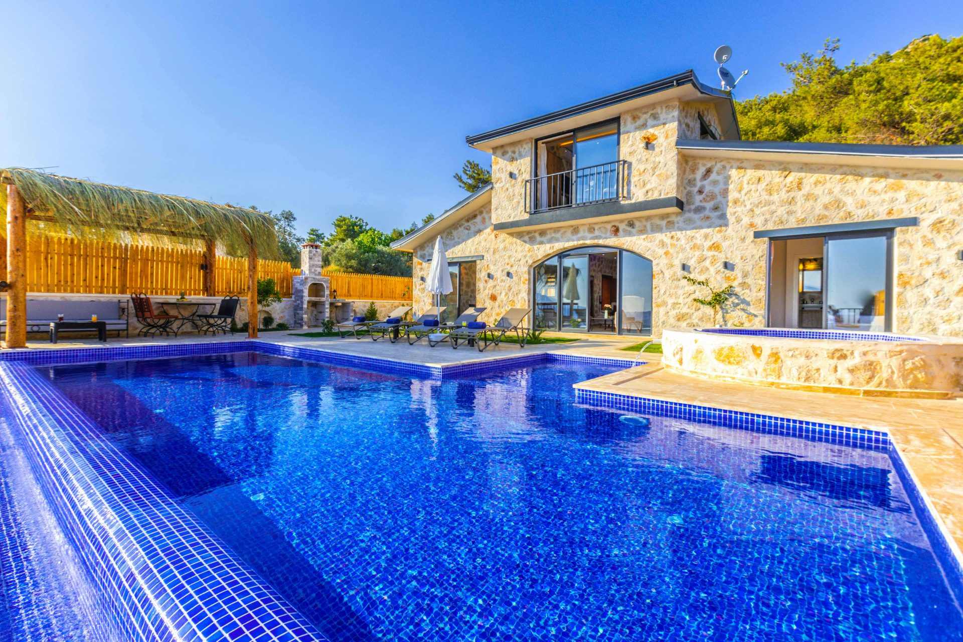 Una hermosa villa de piedra con una impresionante piscina azul y exuberante vegetación.