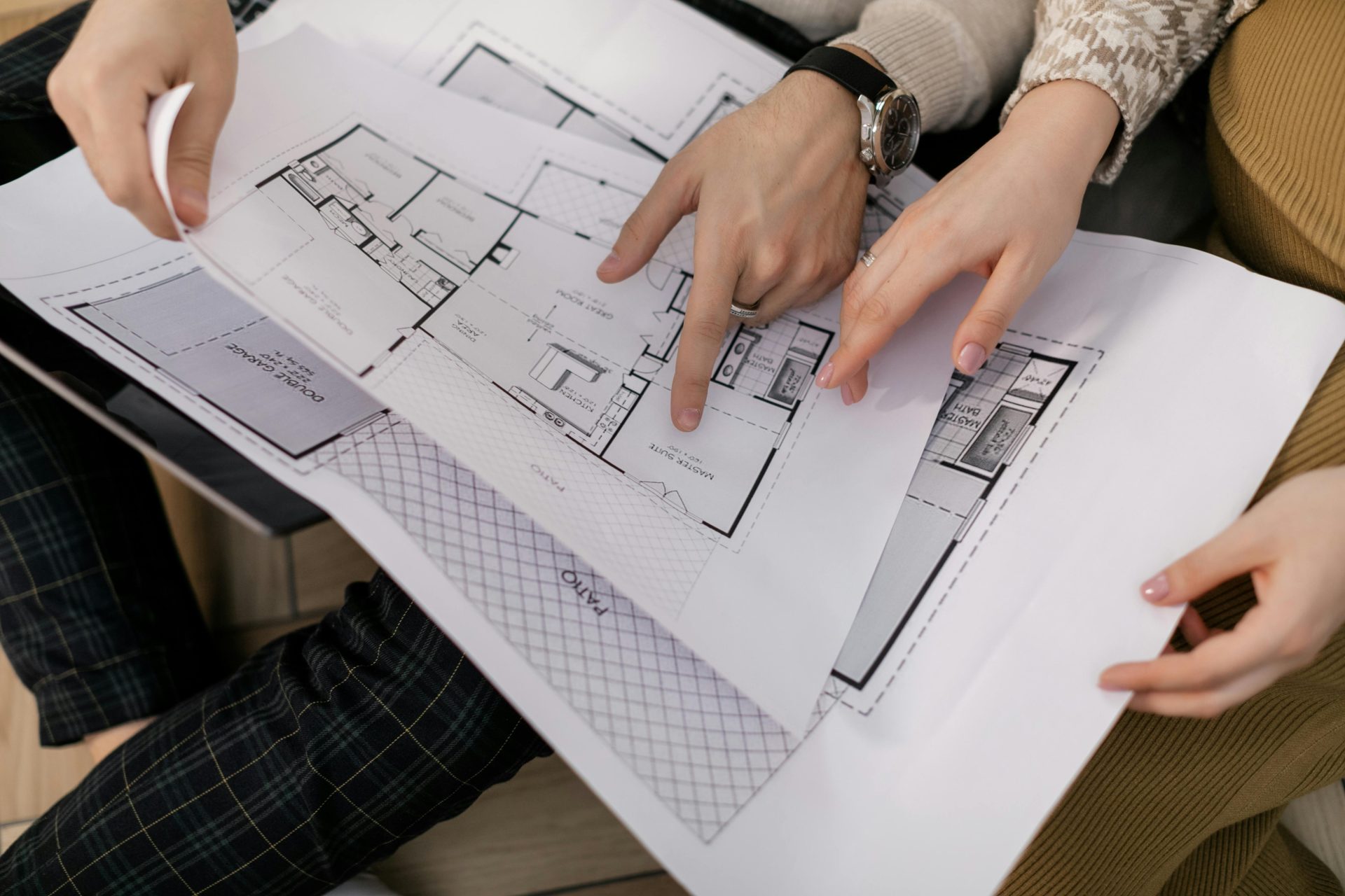 Manos de arquitectos e ingenieros revisando planos de construcción de viviendas